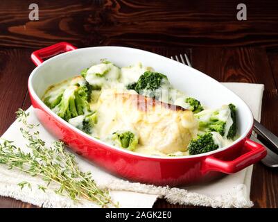 Hähnchenbrustfilet überbacken mit Broccoli in bechamelsauce Soße auf einem dunklen Holztisch. Gesunde Nahrung, sauberes Essen, Seitenansicht. Stockfoto