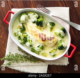 Hähnchenbrustfilet überbacken mit Broccoli in bechamelsauce Soße auf einem dunklen Holztisch. Gesunde Nahrung, sauberes Essen, Ansicht von oben. Stockfoto