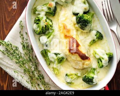 Hähnchenbrustfilet überbacken mit Broccoli in bechamelsauce Soße auf einem dunklen Holztisch. Gesunde Nahrung, sauberes Essen, Ansicht von oben. Stockfoto