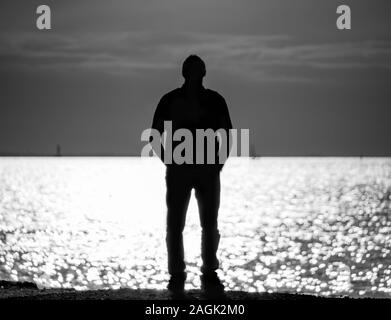 Silhouette eines Mannes auf den Golf von Finnland in St. Petersburg, ein Mann, der in die Ferne schauen, träumen vom Meer. Selektiver Fokus, monochromes Bild Stockfoto