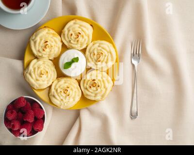 Diät Käse Pfannkuchen, rose Form, auf gelbem Teller mit Kaffee, Himbeeren auf Textilien Leinen Servietten, Ansicht von oben. Diät Frühstück Stockfoto