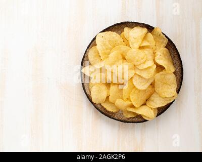 Braun gelb Chips aus natürlichen Kartoffel in Braun Keramikplatte auf weißem Holz- Hintergrund, Ansicht von oben, Nahaufnahme, Kopie Raum Stockfoto