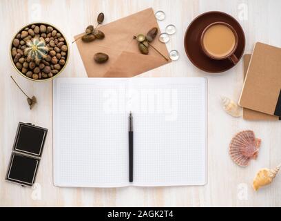 Öffnen Sie Notepad, weiß Kraftpapier Umschlag, Tasse Kaffee und Kaktus im Topf liegen auf einem beige Schreibtisch aus Holz, Flach, Copyspace Stockfoto