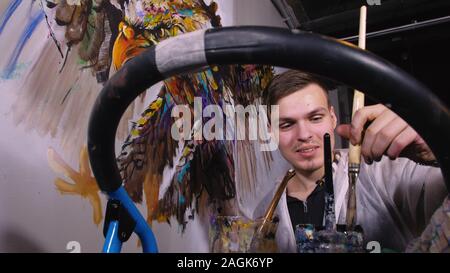 Künstler Designer zieht ein Adler an der Wand. Handwerker Dekorateur malt mit Acryl öl Farbe. Maler Maler gekleidet in Lack auftragen. Indoor. Stockfoto