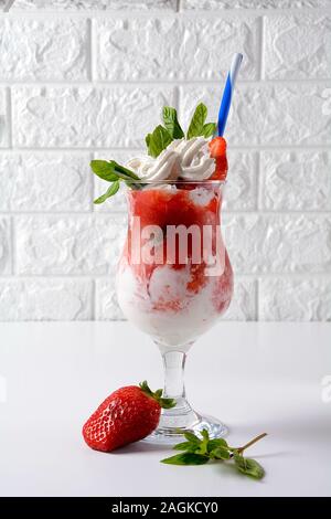 Erdbeerdessert mit Schlagsahne, Eis und Minze in einer Glastasse serviert Stockfoto