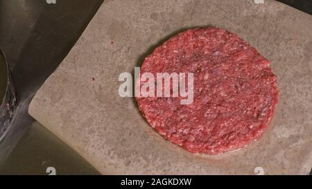 Kochen macht Fleisch Medaillons für Burger. Koch in schwarz Handschuhe macht Schnitzel essen. Die koteletts sind in Stahl Ring in eine noch Medaillon eingeebnet. Stockfoto