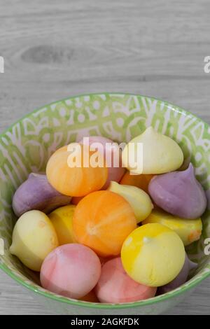 Baisers, verschiedene Farben, in einem grün gemusterten Schüssel Schüssel. Graues Holz Hintergrund Stockfoto
