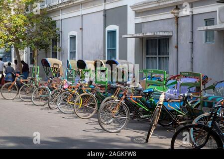 Eine Zeile des Zyklus rikschas am Straßenrand in Puducherry, Tamil Nadu, Indien geparkt Stockfoto