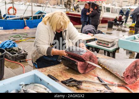 Marseille, Frankreich - 30. November 2018: Frisch und roh großen Thunfischen in Stücke Schnitt durch einen Verkäufer in einem Fischmarkt im regnerischen Wetter in Marseill Stockfoto