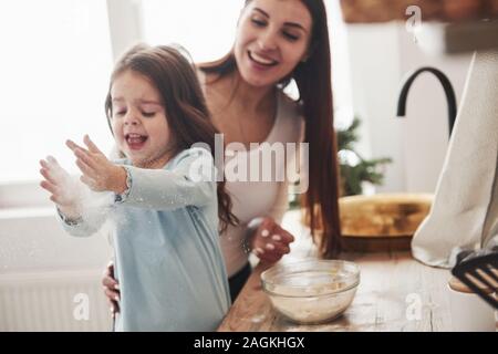 Glückliche Tochter und Mutter vorbereiten Backwaren zusammen. Kleiner Helfer in der Küche Stockfoto
