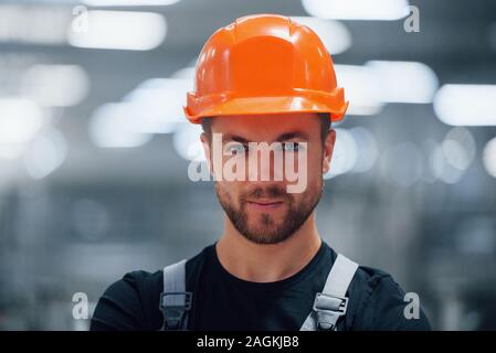 Portrait der männlichen Industriearbeiter im Innenbereich im Werk. Junge Techniker mit orange Schutzhelm Stockfoto