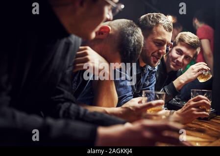 Mann fühlt sich schrecklich. Freunde in der Kneipe mit Alkohol ruht in den Händen. In Gespräch Stockfoto