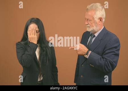 Ausgereifte multi-ethnischen Geschäft Paar gegen braunen Hintergrund Stockfoto