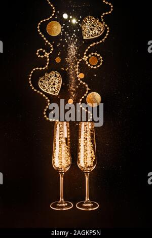 Gläser mit Champagner Wein aus goldenen Dekorationen, Herz auf schwarzem Hintergrund Valentinstag Geburtstag und Konzept Stockfoto