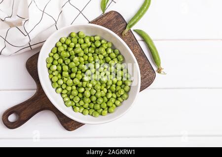 Eine Schale mit frischem grünen Erbsen auf dem weißen Tisch Stockfoto