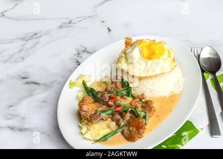 Cremige gesalzene Ei gebratenes Huhn mit Reis und Ei. Asien Essen auf dem Tisch. Stockfoto