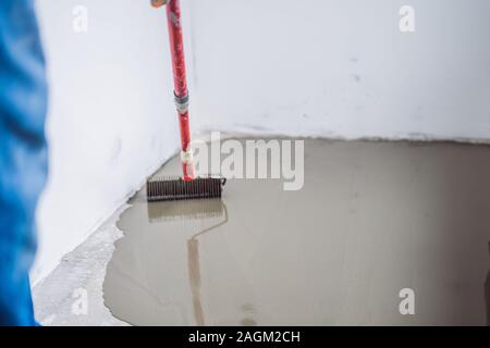 Gipser während des Bodenbelags arbeitet mit selbstnivellierenden Zementmörtel Stockfoto