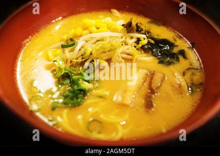 Gelbe Miso Suppe mit Sojabohnen, Algen, Mais, Ramen und Hähnchen in Ton Schüssel, Japan Stockfoto