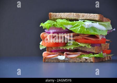 Frisches Sandwich mit Schinken, Tomaten, Salat, Zwiebel auf schwarzem Hintergrund Stockfoto