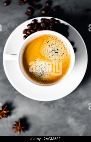 Zusammensetzung mit einer Tasse Kaffee in Bohnen auf graue Tabelle umgeben. Stockfoto