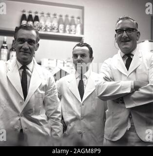 1960er Jahre, historisch, drei Barkeeper im Hemd und Krawatten und traditionelle weiße Servierjacken, die für ein Foto zusammenstehen, England, Großbritannien. Stockfoto