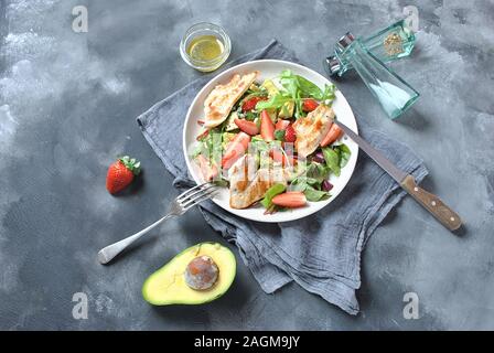 Hühnersalat mit Avocado, Erdbeeren, Blauschimmelkäse, Rucola, Rübenblättern. Gesundes Mittagessen Avocado Schüssel, Teller mit Huhn und Erdbeeren Stockfoto