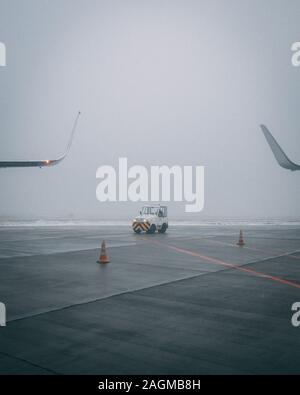 Vertikale Aufnahme einer Flugbahn an einem launischen Tag Mit einem kleinen Auto vom Flughafenpersonal Stockfoto