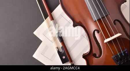 Geige und Bogen mit Noten von schwarzen Tisch. Ansicht von oben. Horizontale Komposition. Stockfoto