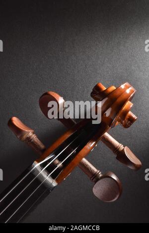 Violine Wirbelkasten und Bogen auf Schwarz strukturierte Tabelle Ansicht von Oben. Vertikale Komposition. Stockfoto