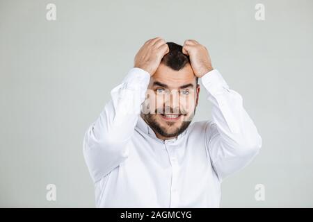 Bärtiger Mann hält die Hand auf den Kopf auf grauem Hintergrund. Mann vergessen über etwas Stockfoto