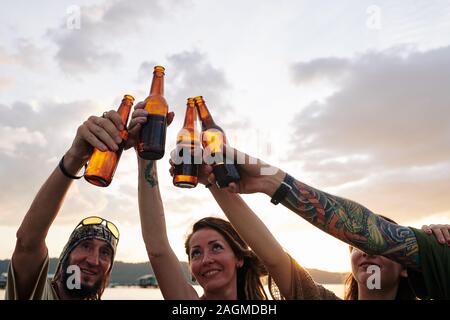 Fröhliche Freunde Toasten und Bierflaschen klirren, wenn Party am Strand Stockfoto