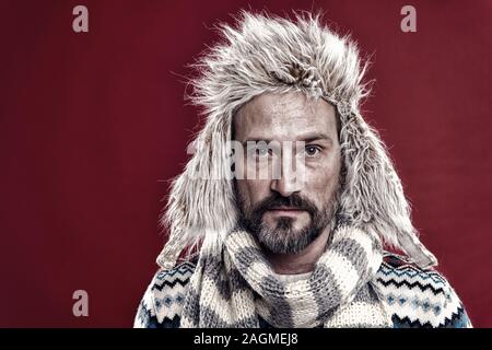 In seinem eigenen Stil. Reifen stattlichen Hipster mit Bart und Schnurrbart gerne ungewöhnliche Dinge tragen. Man bärtige hipster Verschleiß furry Hut gestreiften Schal und gestrickte Pullover. Hipster Mode Winter Zubehör. Stockfoto