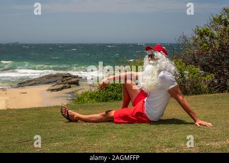 Santa Claus hält Geschenkboxen mit dem Ozean auf backgraund. Australien, Weihnachten im Sommer. Stockfoto