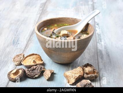 Japanische Miso-Suppe mit frischem Thunfisch, getrockneten Algen, Tofu, Shiitake getrockneten Pilzen in einer Holzschüssel auf dem Holzhintergrund Stockfoto