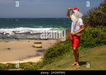 Santa Claus hält Geschenkboxen mit dem Ozean auf backgraund. Australien, Weihnachten im Sommer. Stockfoto