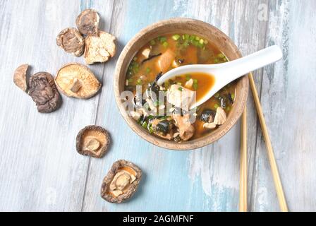 Japanische Miso-Suppe mit frischem Thunfisch, getrockneten Algen, Tofu, Shiitake getrockneten Pilzen in einer Holzschüssel auf dem Holzhintergrund Stockfoto