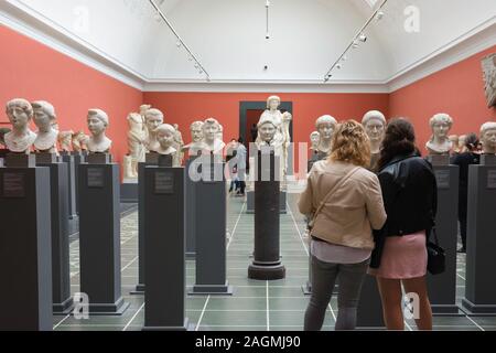 Frauen Museum, Ansicht von hinten von zwei jungen Frauen, die Freunde an der alten römischen Büsten in der Ny Carlsberg Glyptotek Museum in Kopenhagen, Dänemark. Stockfoto