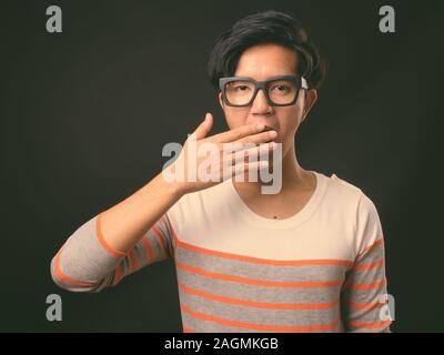 Die Jungen gut aussehenden asiatischer Mann auf schwarzem Hintergrund Stockfoto