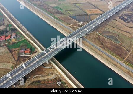 Jingmen. 20 Dez, 2019. Luftbild am Dez. 20, 2019 zeigt die Jianghan Kanalbrücke des Zaoyang-Qianjiang Expressway in der zentralen Provinz Hubei China übernommen. Der Bau der 244 km langen Zaoyang-Qianjiang Expressway ist bald abgeschlossen, mit seiner Geschwindigkeit ausgelegt auf 100 Kilometer pro Stunde. Die Schnellstraße wird verkürzt sich die Reisezeit zwischen nördlichen und südlichen Hubei Hubei. Credit: Jin Liangkuai/Xinhua/Alamy leben Nachrichten Stockfoto