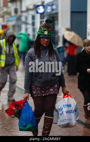 Ashford, Kent, Großbritannien. 20 Dez, 2019. UK Wetter: eine Frau beladen mit Shopping in der regen Ashford Stadt High Street Spaziergänge. © Paul Lawrenson 2019, Foto: Paul Lawrenson/Alamy leben Nachrichten Stockfoto