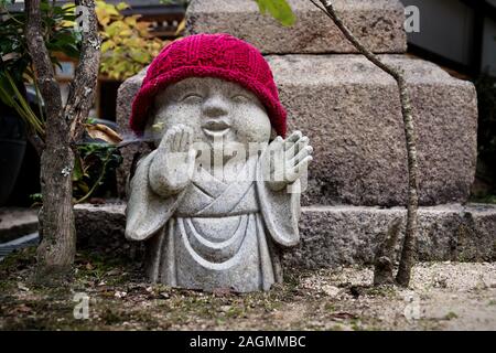 Rakan Statue mit Red Hat und Bäume im Daishoin Tempel auf der Insel Miyajima, Japan. Stockfoto