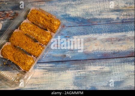 Vier Kuchen in einem Kunststoffbehälter auf einer hölzernen Hintergrund Stockfoto