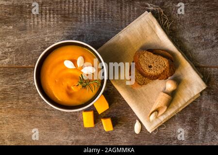 Gesunde Kürbiscreme Suppe auf einem rustikalen Holztisch. Herbst Kürbis creme Suppe mit Rosmarin Kräuter und Croutons. Platz kopieren Stockfoto
