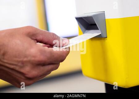 Nahaufnahme eines jungen kaukasischen Mann seinen Zug oder U-Bahn Ticket Validierung in einer Maschine Stockfoto