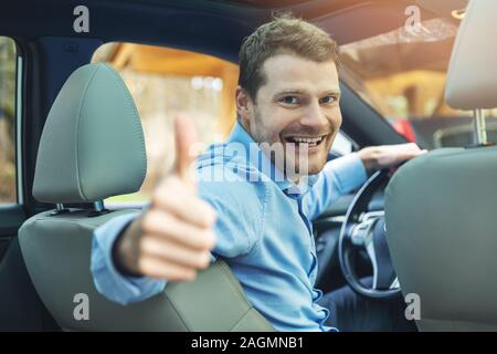 Mann sitzt im Auto und zeigen "Daumen hoch" Geste Stockfoto