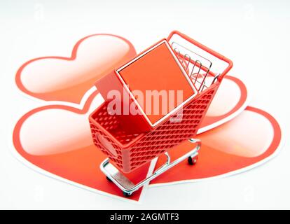 Warenkorb mit einem Geschenk Box auf einem Hintergrund von Papier Herzen Stockfoto