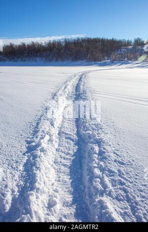 Trail von einem Schneemobil auf einem gefrorenen und Snowy River Bed. Stockfoto