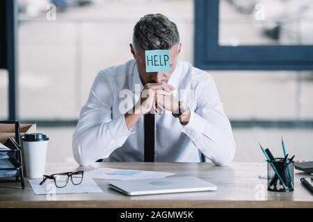 Geschäftsmann in Anzug sitzen mit Zettel auf der Stirn Stockfoto