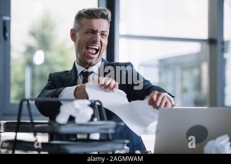 Selektiver Fokus gereizter Mann Zerreißen von Papier im Büro Stockfoto