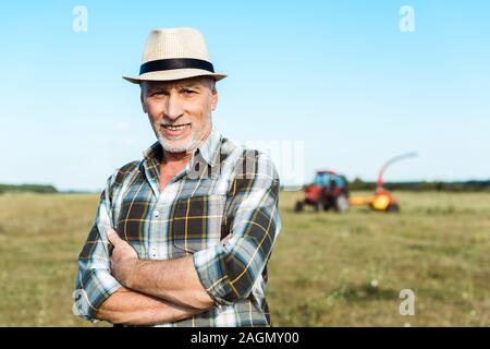 Happy senior Bauer stand mit verschränkten Armen im Feld Stockfoto